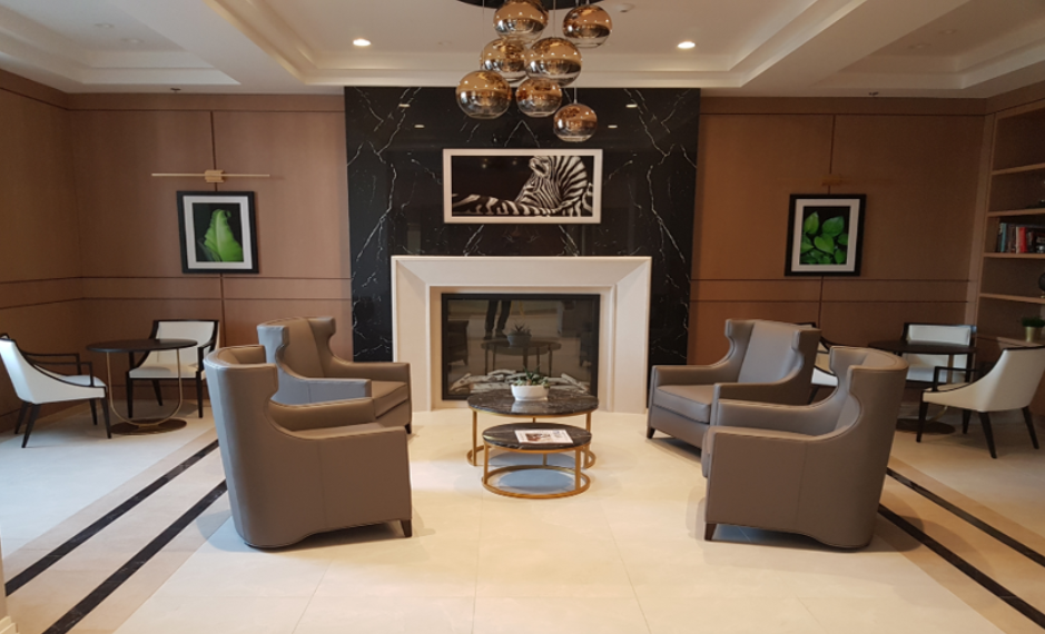 Grand hospitality lounge with symmetrical leather armchairs, marble fireplace and modern chandelier